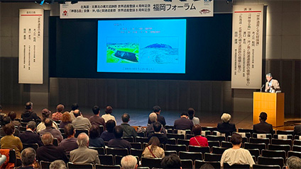 福岡論壇一幕:講者向觀眾發言時,影像投射喺幕上。