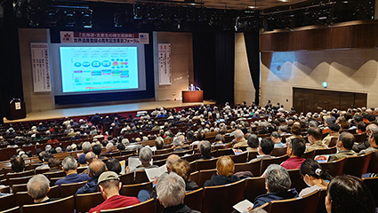 東京論壇現場一幕:喺場地被指定為世界遺產嗰陣影嘅相片,投射喺幕上,講者同時向觀眾發言。